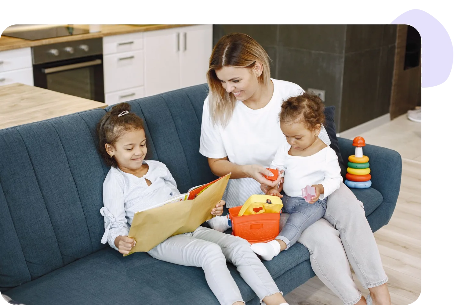 Mother reading a picture book with her two young daughters on the sofa
