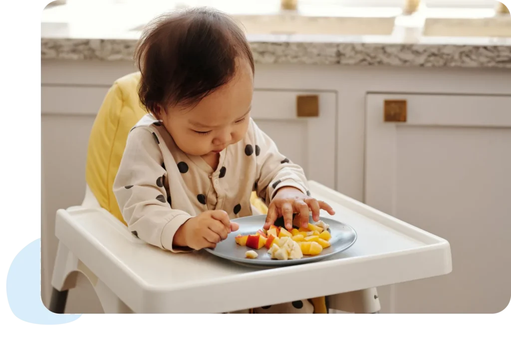 A cute toddler in a polka dot outfit enjoying a healthy fruit snack indoors.